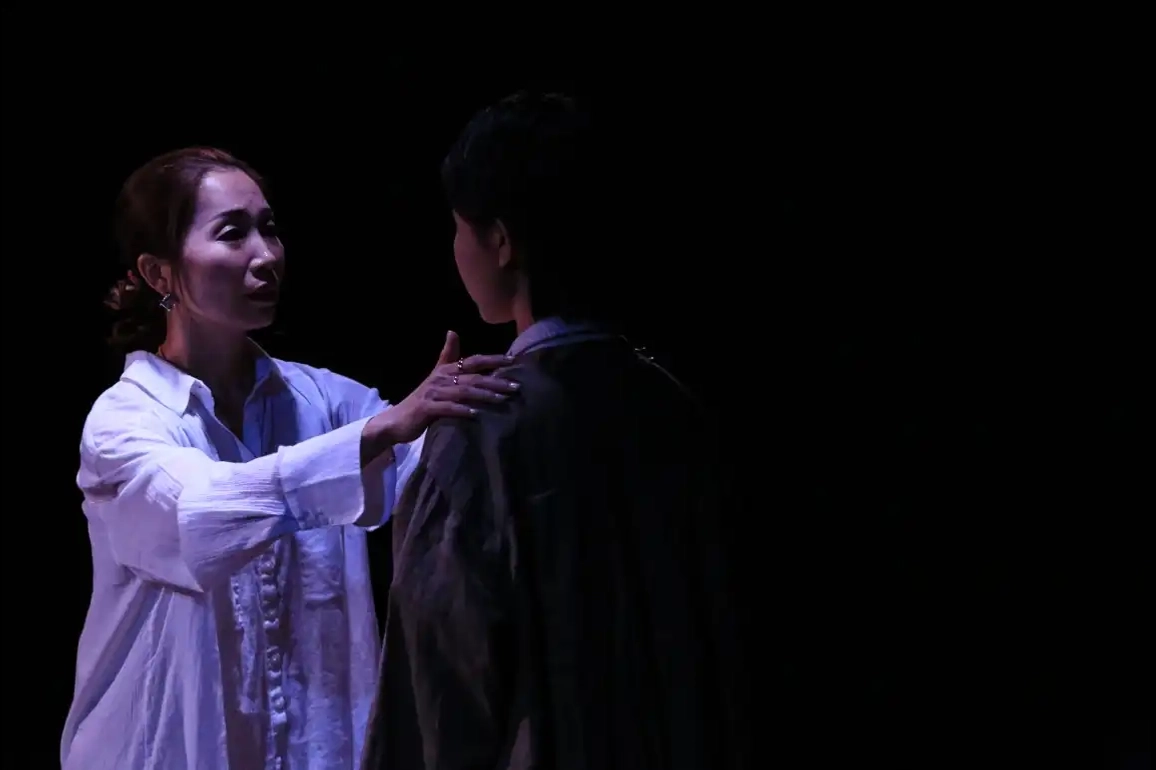 Two characters speak to each other with dark, high contrast lighting