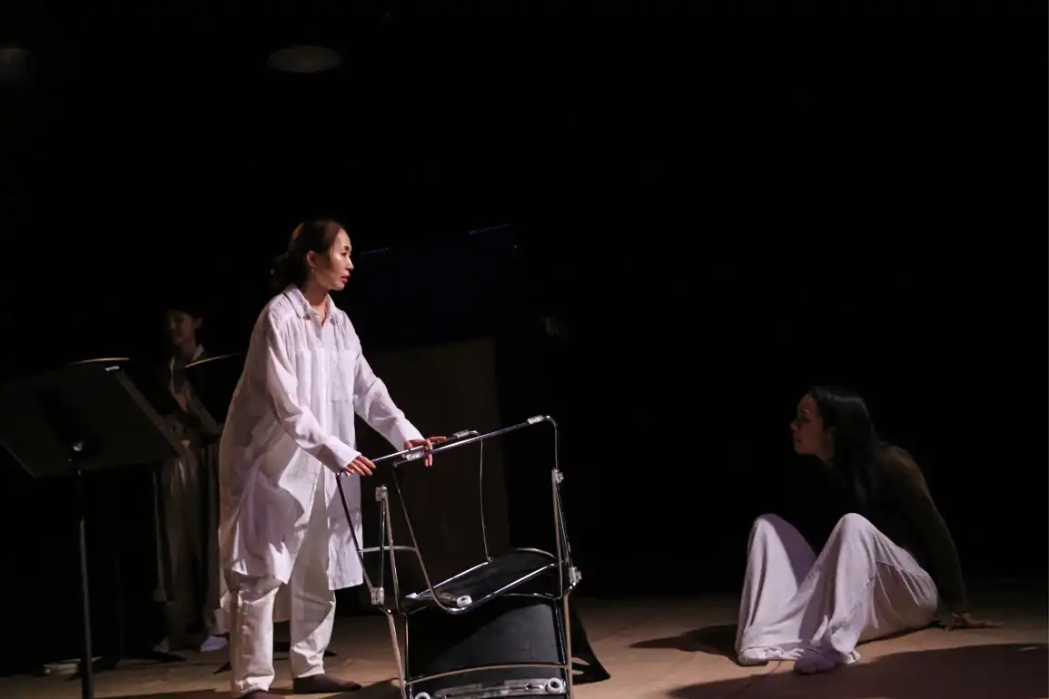 Character holds flipped chair on the floor, while daughter sits on the floor looking up to her
